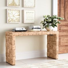 a table with some books and a plant on it in front of a wall mounted pictures