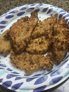 some fried food on a paper plate sitting on a granite counter top with blue and white polka dots