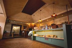 the inside of a coffee shop with lots of counter space and lights hanging from the ceiling