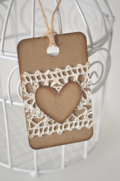 a heart shaped cookie hanging from a string on a white wire holder with twine