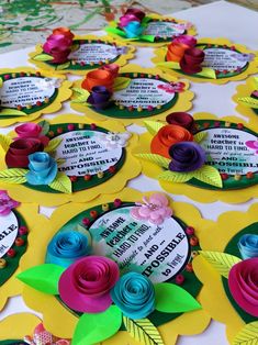 many colorful paper flowers on a table with some words in the center and one flower at the top