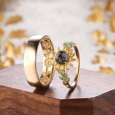 two wedding rings sitting on top of a wooden table next to gold flowers and leaves