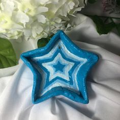 a blue and white star shaped dish sitting next to some flowers on a white cloth