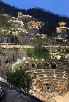 an outdoor seating area is lit up at night with string lights on the balcony and stairs