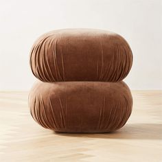 two large round cushions sitting on top of a wooden floor in front of a white wall