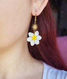 a woman with red hair wearing white and yellow earrings