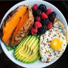 a plate with eggs, avocado, and berries on it next to bread