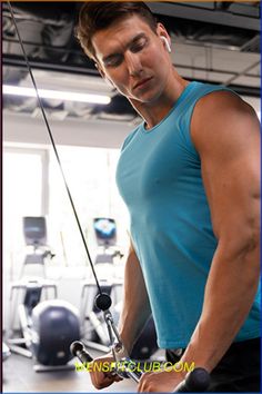 a man in the gym is using his cell phone and holding a rope with both hands