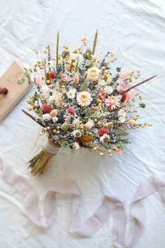 a bouquet of flowers sitting on top of a white table cloth next to a piece of wood