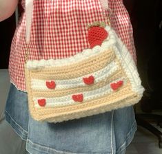 a crocheted purse with strawberries and hearts on the front is being held by a woman