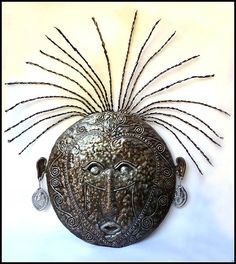 a metal mask with feathers on it's head is displayed against a white background