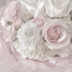 a bouquet of white and pink flowers sitting on top of a tableclothed cloth