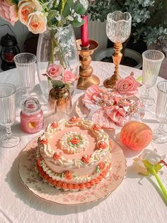 a table topped with a cake covered in frosting next to vases filled with flowers