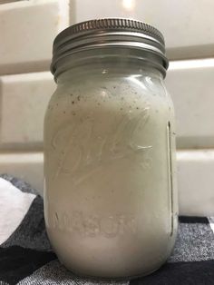 a mason jar filled with white liquid sitting on top of a checkered table cloth