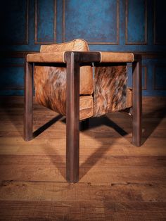 an animal print leather chair sitting on top of a wooden floor next to a blue wall