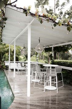 an outdoor dining area with tables and chairs under a covered patio next to a pool