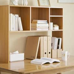 a wooden desk topped with books and a laptop computer next to a book shelf filled with books