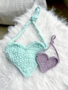 two crocheted hearts hanging from a hook on a white furnishing pillow