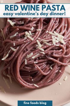 A plate of red wine pasta topped with parmesan cheese.