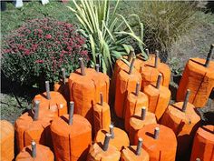 many orange vases are stacked on top of each other in front of a bush