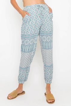 The Francesca Blue and White Boho Print Joggers are the must-have, comfy joggers you need in your wardrobe! Lightweight woven fabric, in a blue, teal, plum, and white bohemian print, shapes these stylish joggers with an elastic, high waist (with drawstring front-tie detail for a perfect fit) atop tapered pant legs with a fitted, elastic hem. Two side pockets, sit below the elastic waist. Casual Patterned Beach Pants, Summer Patterned Bottoms For Loungewear, Casual Printed Blue Bottoms, Casual Blue Printed Bottoms, Printed Patterned Bottoms For Beach Season, Blue Printed Bottoms For Vacation, Printed Blue Bottoms For Vacation, Blue Harem Pants For Beach In Spring, Blue Printed Long Pants