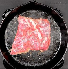 a piece of meat is cooking in a skillet