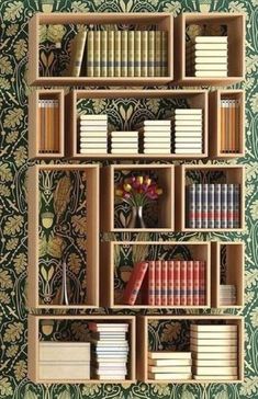 a bookshelf filled with lots of books next to a wallpapered wall