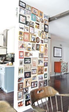 there is a wall with many pictures on it in the living room and kitchen area