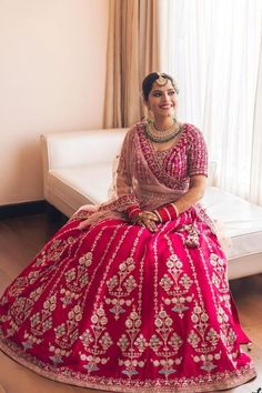 a woman sitting on top of a white couch wearing a red and gold wedding dress