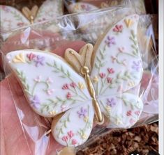 there is a hand holding some cookies in the shape of a butterfly with flowers on it