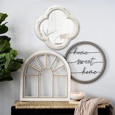 two mirrors on the wall above a bench with a candle and potted plant next to it