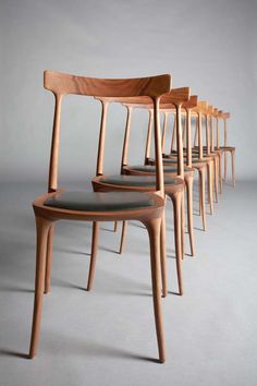 six wooden chairs lined up in a row on a gray surface with one chair facing the camera