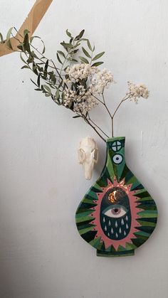 there is a vase with flowers in it and a skull on the wall next to it