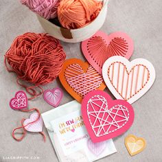 heart shaped paper cutouts sitting on top of a table next to yarn and crochet hooks