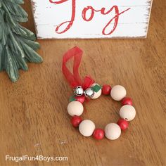 a christmas wreath made out of beads on a table next to a sign that says joy