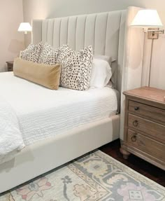 a bed with white sheets and pillows in a bedroom next to two lamps on either side of the bed