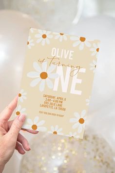 a person holding up a card with the words olive and daisy on it in front of balloons