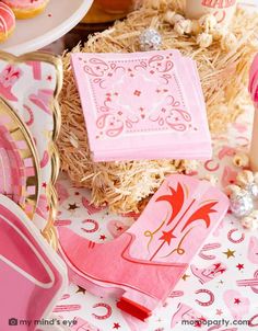 pink napkins and plates on a table with cupcakes in the background at a princess birthday party