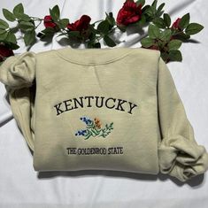 Stay warm and look stylish with this unique Kentucky the Goldenrod State embroidered  at the center of the chest This piece of clothing is perfect for any casual occasion. The high-quality fabric keeps you warm and comfortable, while the intricate embroidery brings a touch of elegance and charm to any ensemble. Whether you're out and about or just lounging at home, this sweatshirt is sure to make you stand out from the crowd. The sweatshirt also features a classic crew neckline and long sleeves Fall Fleece Sweatshirt With Embroidered Text, Fall Fleece Sweater With Embroidered Text, Fall Embroidered Text Fleece Sweater, Embroidered Fleece Sweatshirt For Fall, Goldenrod Flower, Kentucky Sweatshirt, Army Gifts, Flower Sweatshirt, Golden Rod