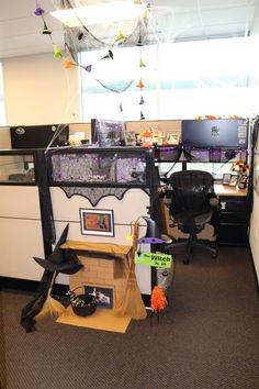 an office cubicle decorated for halloween with decorations on the desk and hanging spider webs