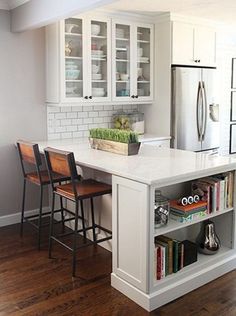 a kitchen with white cabinets and an island that has bookshelves on top of it