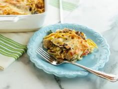 a blue plate topped with lasagna next to a casserole dish