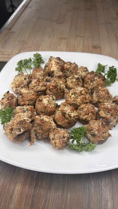 a white plate topped with meatballs and parsley on top of a wooden table