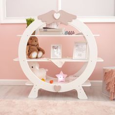 a teddy bear sitting on top of a white shelf next to a pink and white wall