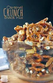 a glass bowl filled with caramel crunch snack mix on top of a wooden table