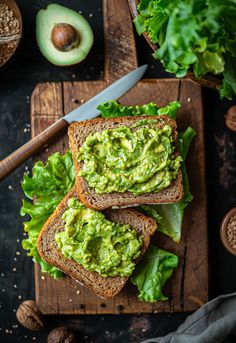 two pieces of bread with guacamole spread on them next to an avocado cut in half