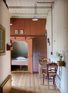 a room with wooden floors and walls has a bunk bed in the corner between two tables