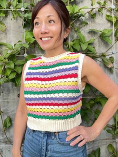 a woman standing in front of a wall with ivy growing on it and smiling at the camera