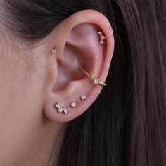 a woman wearing three different types of ear piercings on her left side of the ear