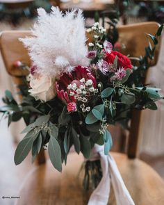 a bouquet of flowers sitting on top of a wooden table in front of a chair